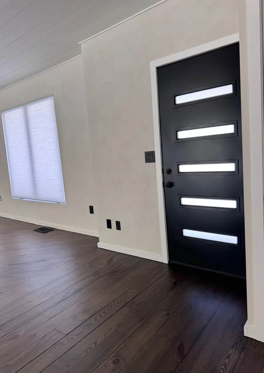Dark stained hardwood floor by a black front door